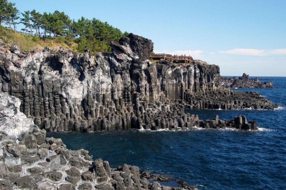 濟州島著名的柱狀節理景觀，壯觀的火山熔岩形成獨特的六邊形石柱，與湛藍的海洋交匯成一幅迷人的自然畫面
